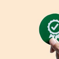 a hand holding up a compliance check badge