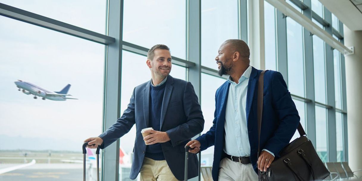 Two businessmen walking through a departures airport terminal