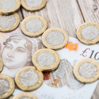 A group of pound coins on a £10 note